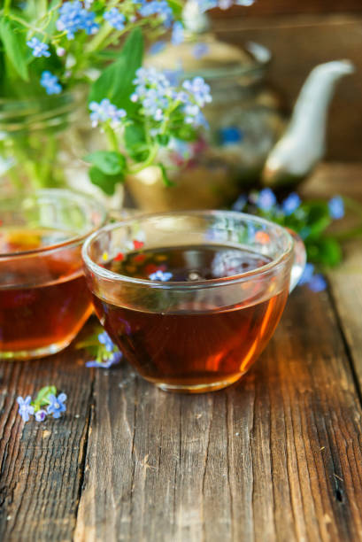 istock Romantic background with cup of tea ,lilac flowers and open book over white table 929775244