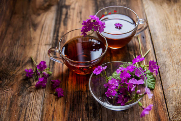 istock Glass cup of tea on old wooden surface. Small white flowers. 929776708