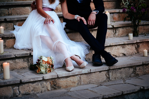 Close-up of newlywed couple's feet sitting on stone stairs and relaxing at wedding reception