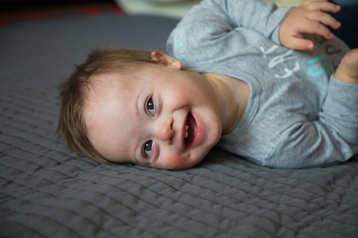 Closeup portrait of perfect, beautiful baby girl with pink lips and cheeks, blue eyes and peach fuzz hair. She is looking at the camera with a slight smile.