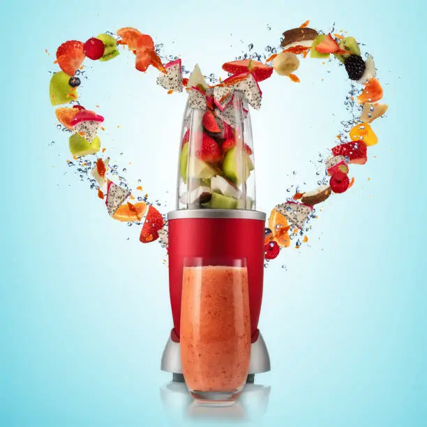 Smoothie mixer with drink and fruit flying ingredients in heart shape, isolated on gradient background. Healthy drink and lifestyle
