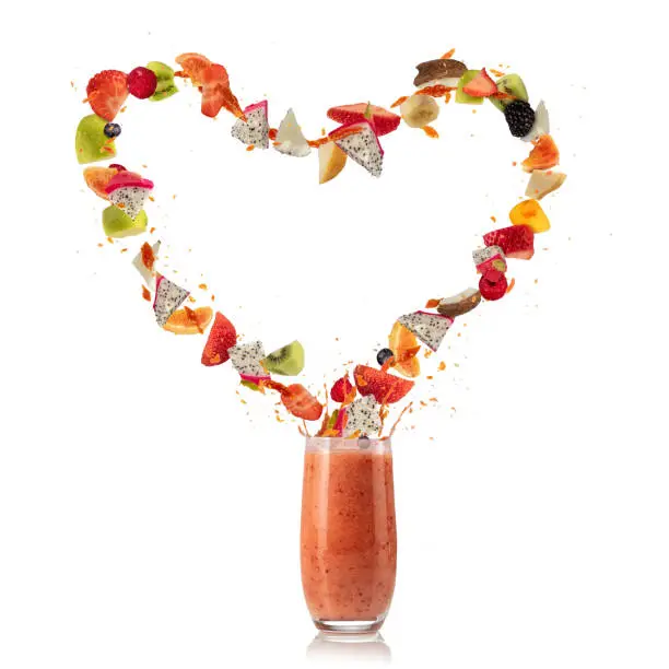 Smoothie drink with fruit flying ingredients in heart shape, isolated on white background. Healthy drink and lifestyle