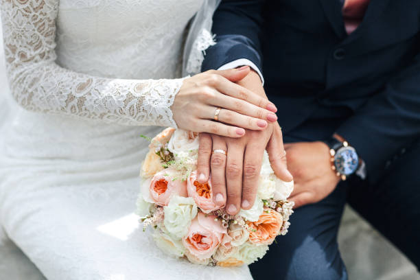 istock Bride hands with ring . Newlyweds put their hands on the bouquet 929787372