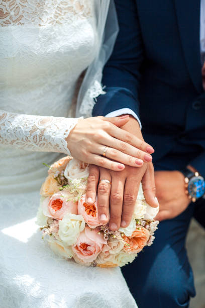 istock Bride hands with ring . Newlyweds put their hands on the bouquet 929787436
