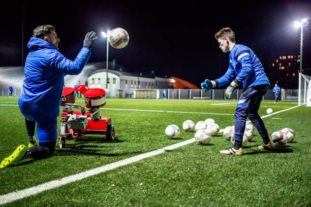 istock Goalkeeper Helping his Coach Using Soccar Ball Cannon at Training 929790398