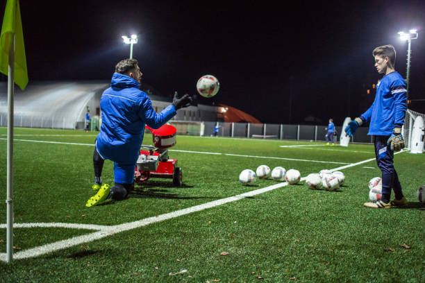 istock Goalkeeper Helping his Coach Using Soccar Ball Cannon at Training 929790408