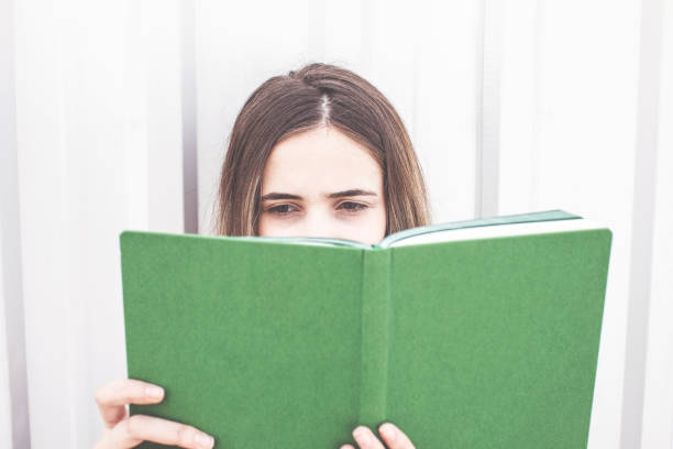 istock Young woman reading book outside 929792960