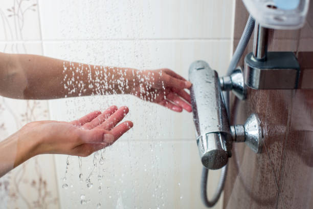 Hands of a young woman taking a hot shower at home stock photo