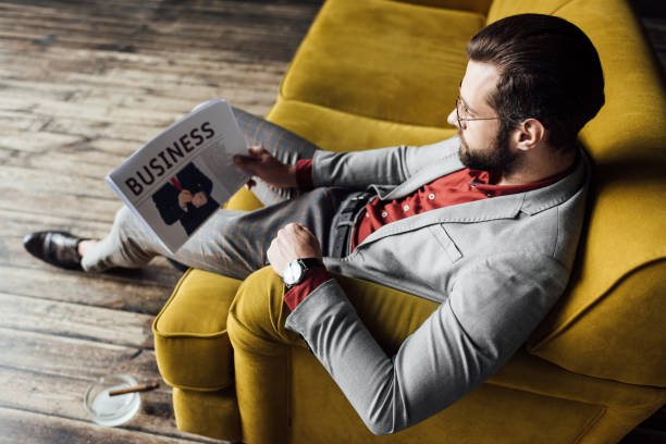 istock stylish man reading business newspaper and sitting on couch 929806110