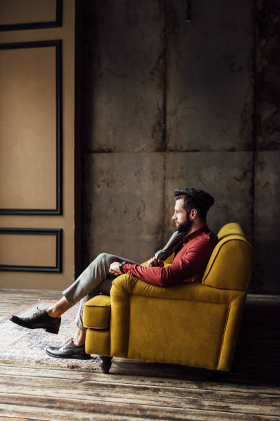 istock fashionable elegant man sitting on yellow sofa 929806588