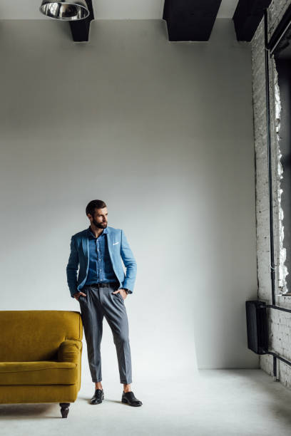 istock thoughtful stylish man posing in blue trendy suit and looking at window 929816462