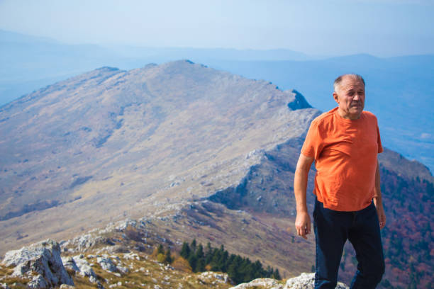 Senor man on top of high mountain.
