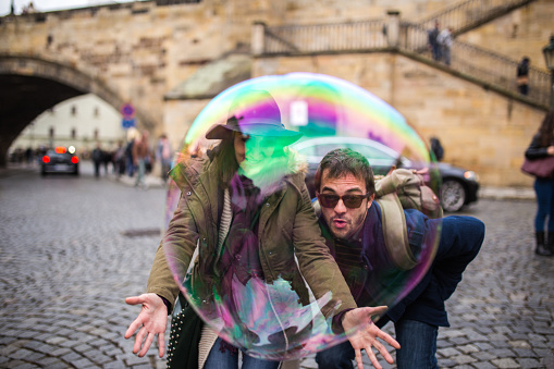 Happy young couple in Prague playing with big size soap balloons