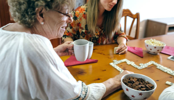 Senior mother and daughter playing domino Senior mother and daughter playing domino in the living room teenage girl with grandmother stock pictures, royalty-free photos & images