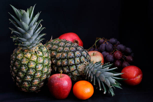 Dark Food - Chiaroscuro lighting on pineapple, grapes, plums apples,  pomegranate and lime with dark background and copy space