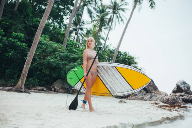 istock beautiful girl in bikini with paddle board on tropical beach 929834382