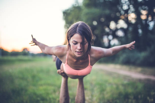 Concentrating Man is holding a woman in plank pose acroyoga stock pictures, royalty-free photos & images