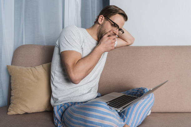 istock yawning overworked freelancer in pajamas working with laptop on couch 929858000