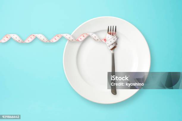 Place Setting With Steel Fork And Measuring Tape On Blue Background Stock Photo - Download Image Now