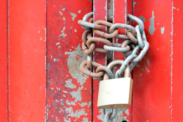 istock Old lockpad locked on a wooden red door with rusty chain close up background. 929876802