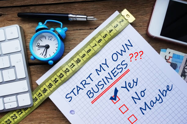 istock Start my own business question, conceptual image with personal agenda, computer keyboard and office objects on wooden table 929876852