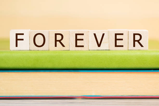 istock Forever word built with letter cubes on green book 929877446