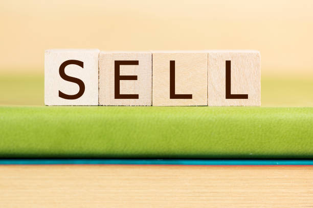 istock Sell written in wooden cubes on a green book 929877448