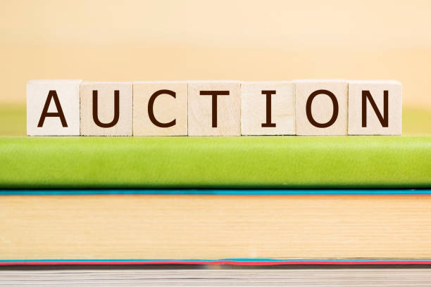 istock Auction word built with letter cubes on green book 929883408