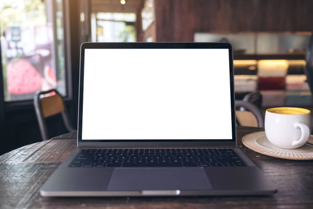 istock Mockup image of laptop with blank white desktop screen and coffee cup on wooden table in modern cafe 929888096