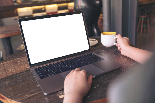 istock Mockup image of a businesswoman using laptop with blank white desktop screen while drinking hot coffee on wooden table in cafe 929888098