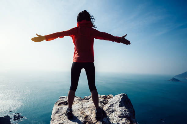 istock freedom female standing on sunrise windy coast 929892190