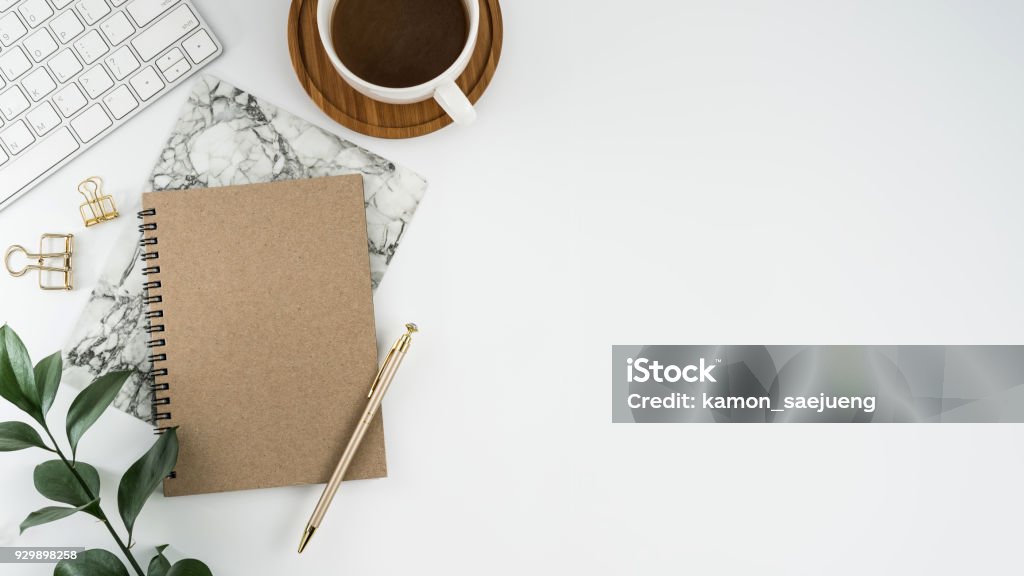 Styled stock photography white office desk table with blank notebook, computer, supplies and coffee cup. Top view with copy space. Flat lay. Desk Stock Photo