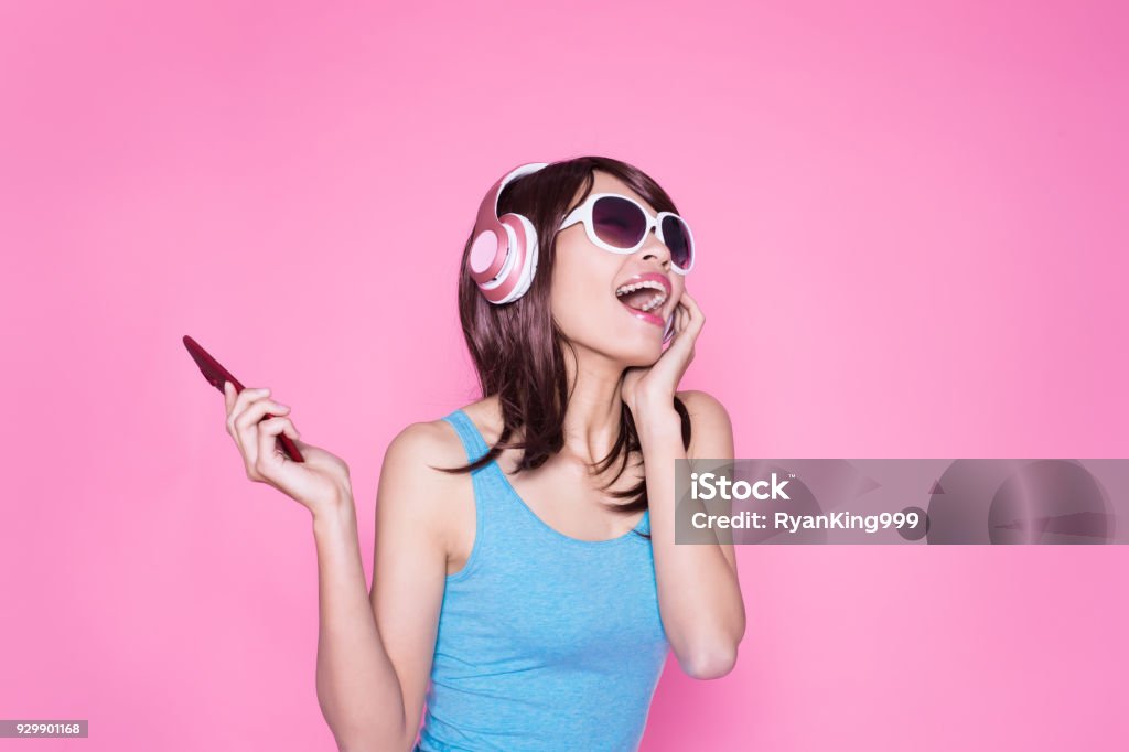 woman use phone listen music woman use phone listen music on the pink background Headphones Stock Photo