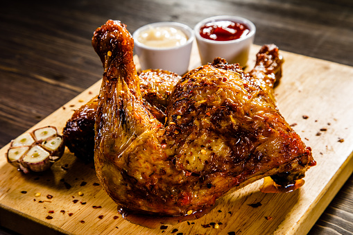 Roast chicken legs with French fries on wooden table