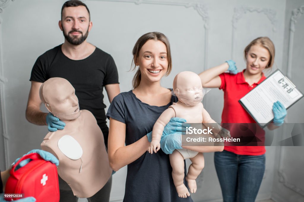 First aid training A group photo of a young people standing together and holding dummies and emergency kits after the first aid training indoors CPR Stock Photo