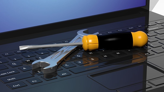 Screwdriver and wrench on laptops keyboard