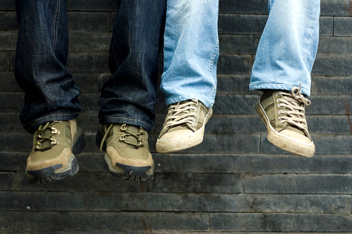 male feet with blue sneakers on the asphalt. light and comfortable denim shoes for summer walks in the fresh air along city streets and country roads