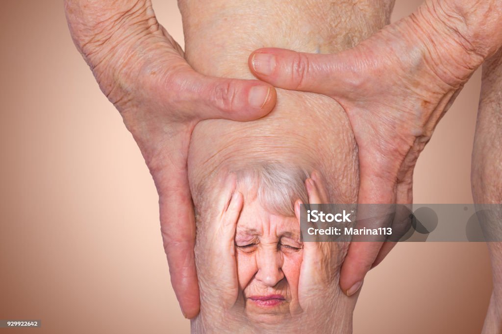 Donna anziana che tiene il ginocchio con dolore - Foto stock royalty-free di Dolore fisico