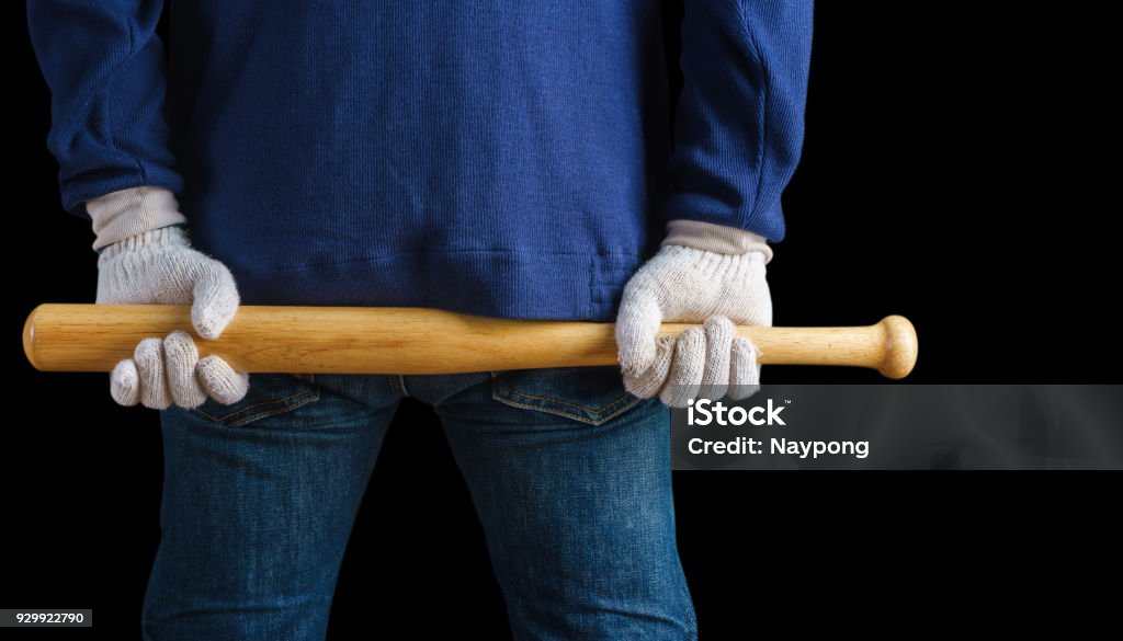 Man holding a baseball bat on black background Baseball Bat Stock Photo