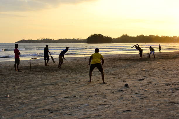 Young boys playing cricket game on a beach Silhouettes of young anonymous boys playing cricket game on Sri Lanka beach. Golden sunset light with sunbeams in Weligama. cricket player photos stock pictures, royalty-free photos & images