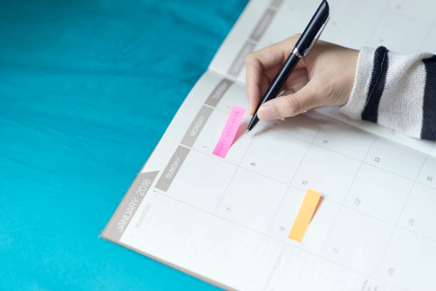 istock Woman planning agenda and schedule using calendar event planner, Writing plan on memo schedule. Woman hands using plan to vacation on Happy New Year 2018. 929934112