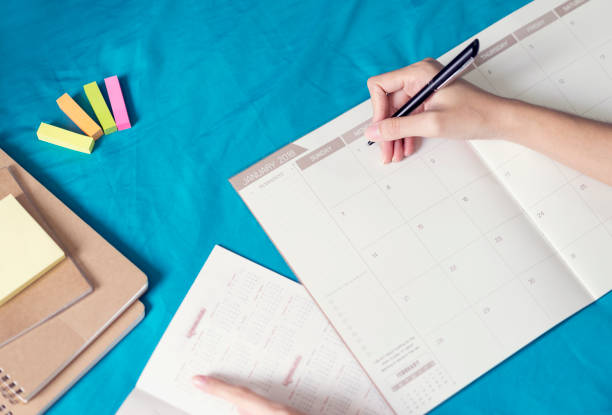 istock Woman planning agenda and schedule using calendar event planner, Writing plan on memo schedule. Woman hands using plan to vacation on Happy New Year 2018. 929934134