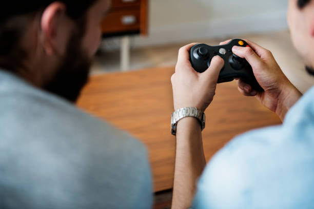 Friendship, technology, games and relaxing time at home concept - close up of male friends playing video games at living room