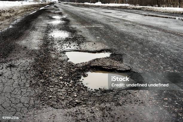 Old Highway With Holes And Snow Landscape Road Potholes In Cloudy Winter Weather Concept Absence Of Timely Repair Of Highway Stock Photo - Download Image Now