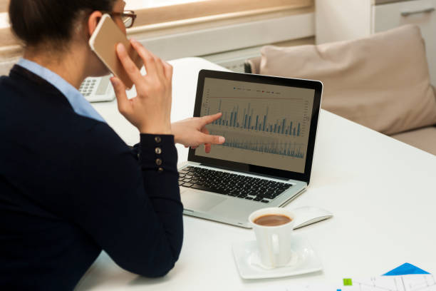 Elegant businesswoman working contemporary notebook while talking on phone
