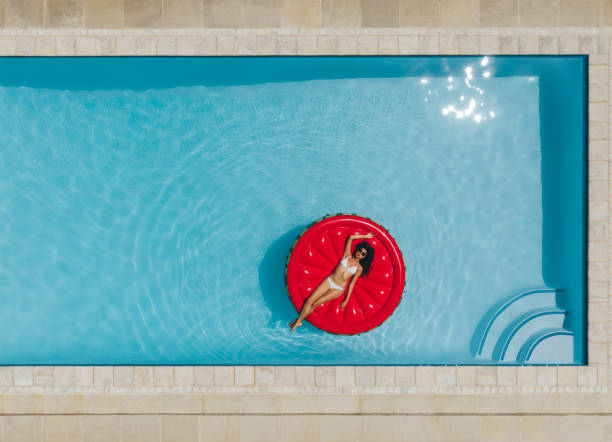 young woman floating on inflatable mattress in pool - bikini summer vacations looking down imagens e fotografias de stock