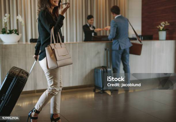 Woman Arriving At Hotel Lobby With Suitcase Stock Photo - Download Image Now - Hotel, Hotel Reception, Business Travel