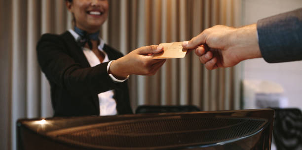 Businessman paying for hotel room at reception Close up of businessman paying with credit card at reception desk in hotel. Business man giving credit card to hotel receptionist for payment of his room. Focus on hands. airport check in counter photos stock pictures, royalty-free photos & images