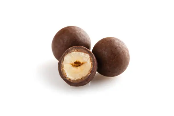 Heap of sugared hazelnuts dragees in chocolate isolated on white background. Handmade chocolate balls candies filled with nuts