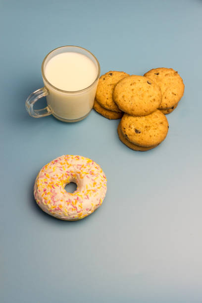 istock Biscuits with chocolate chips, milk and donut in glaze on a yellow plate with a plate on a blue background 929960112